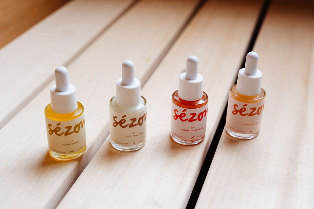 The four Sézon serums in glass dropper bottles on a light wooden table